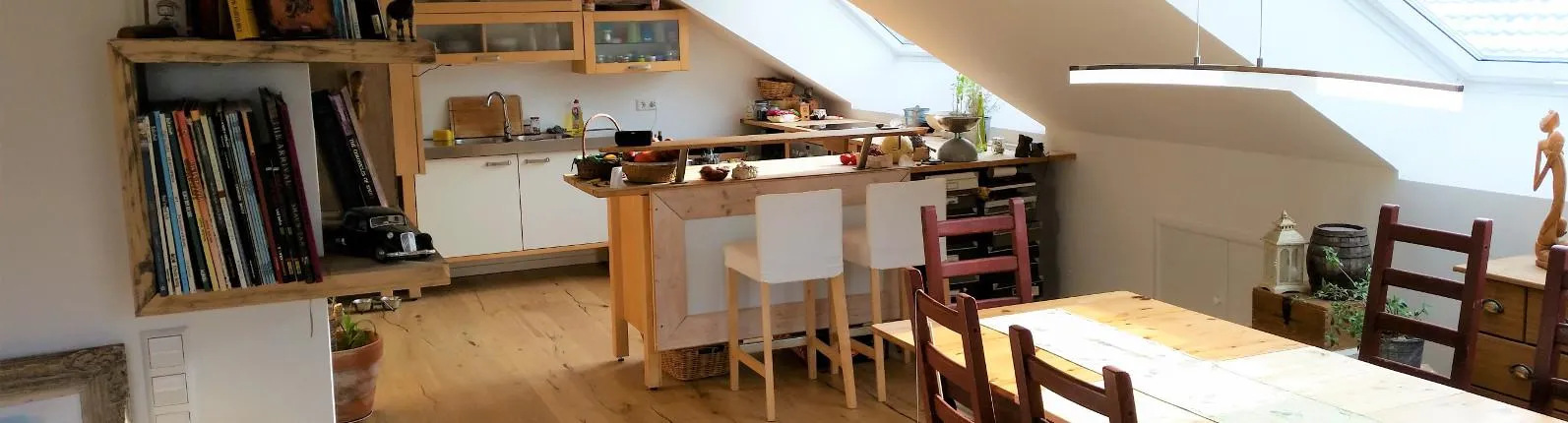 Eine gemütliche Küche und Essbereich in einer Dachgeschosswohnung mit Holzelementen und viel natürlichem Licht. 