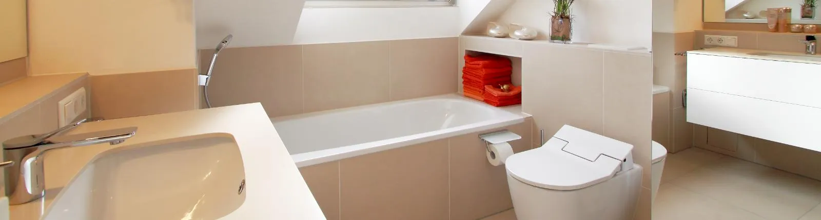 Ein modernes Badezimmer in warmen Beigetönen, ausgestattet mit einer Badewanne, einem wandhängenden WC und einem Waschbecken. 