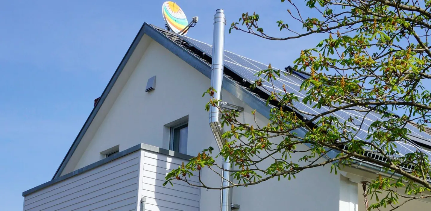 Seitliche Ansicht eines modernen Hauses mit einem geneigten Dach, auf dem Solarpanels installiert sind.
