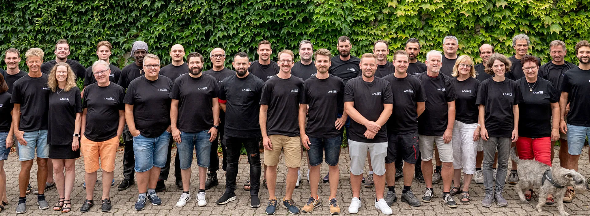 Handwerksteam der Lassen GmbH vor einer bewachsenen Mauer.