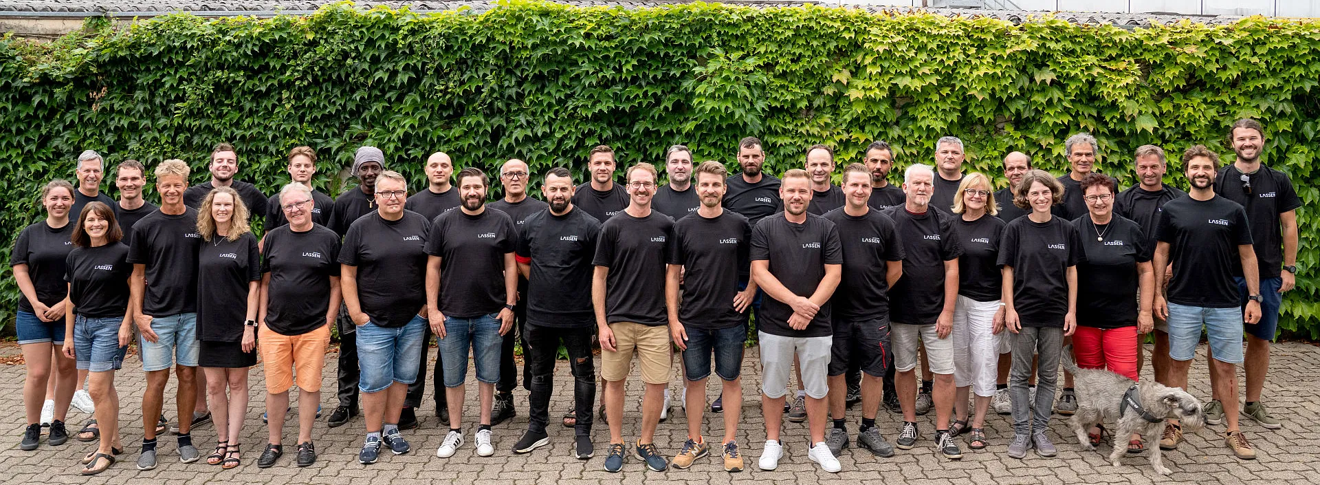Handwerksteam der Lassen GmbH vor einer bewachsenen Mauer.
