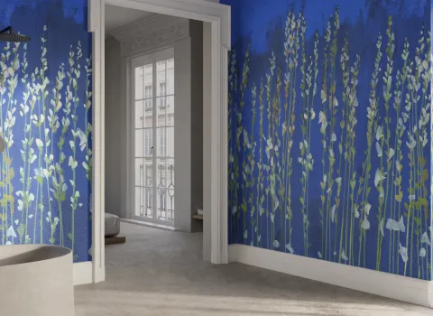 Ein Badezimmer mit einer freistehenden Badewanne und einer auffälligen Wand, die mit einem blauen Hintergrund und langen, gemalten Pflanzenmotiven verziert ist.