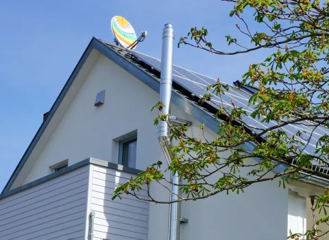 Seitliche Ansicht eines modernen Hauses mit einem geneigten Dach, auf dem Solarpanels installiert sind.