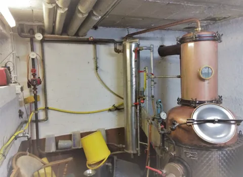 Kupferner Kessel in einem technischen Raum mit Rohrleitungen, Manometern und Ventilen. 