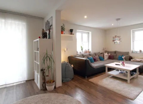 Helles Wohnzimmer mit einer großen Eckcouch, Holzfußboden und modernen Dekorelementen, kombiniert mit einem offenen Raumkonzept und viel natürlichem Licht.