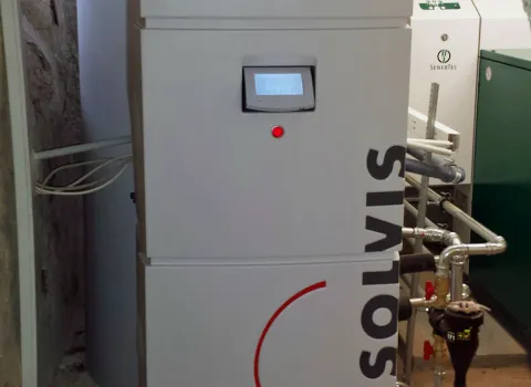 Eine moderne Heizungsanlage der Marke Solvis mit digitalem Display, umgeben von Rohrleitungen und weiteren technischen Geräten in einem Heizungsraum.