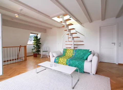 Helles Wohnzimmer im Dachgeschoss mit freitragender Wendeltreppe. 