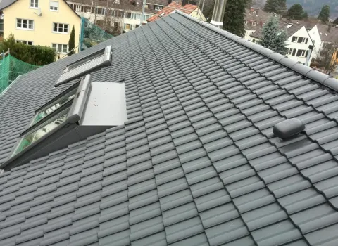 Ein modernes Satteldach mit dunkelgrauen Ziegeln und zwei integrierten Dachfenstern, die Licht ins Innere bringen.