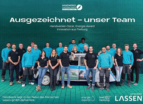 Ein Teamfoto zeigt Mitarbeiter von LASSEN, die stolz vor einem kleinen Fahrzeug posieren.