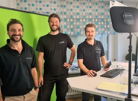 Drei Energie-Experten der Firma Lassen aus Freiburg stehen im Bürozimmer und lächeln in die Kamera.