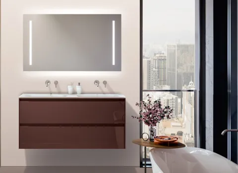 Großzügiger Waschtisch mit dunkler Front, indirekt beleuchtetem Spiegel und Stadtblick im Stocco Designbad.