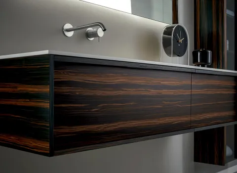 Moderner Waschtisch aus dunklem Holz mit markanter Maserung und wandmontierter Armatur von Stocco.