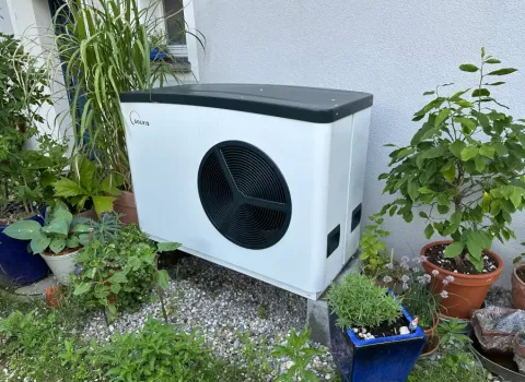 Eine Solvis-Wärmepumpe auf einem Kiesbett im Garten.