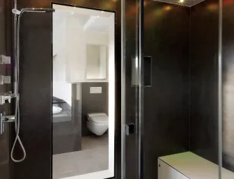 Ein luxuriöses Dampfbad mit gläserner Abtrennung und dunklen Wänden, die für eine moderne Optik sorgen.