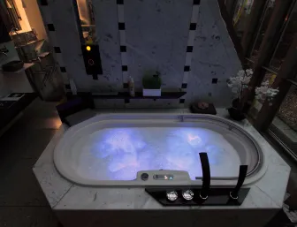 Ein luxuriöser Whirlpool in einem modernen Badezimmer, dessen Wasser in blauer LED-Beleuchtung schimmert. 