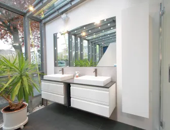 Ein modernes Badezimmer mit einem schwebenden Doppelwaschtisch, der zwei eckige Aufsatzwaschbecken mit metallenen Wasserhähnen umfasst. 