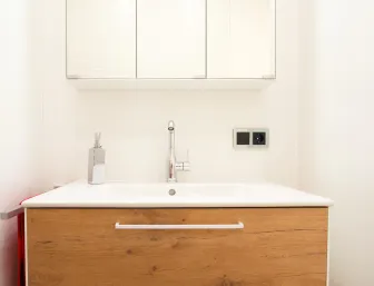 Ein moderner Waschtisch mit einer Front in Holzoptik und einem darüber hängenden Spiegelschrank, der sich perfekt in das minimalistische Design des Badezimmers einfügt.