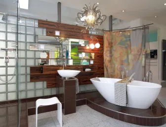 Ein luxuriöses Badezimmer mit einer freistehenden Badewanne auf einer erhöhten Plattform aus dunklen Fliesen.