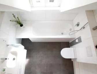 Blick von oben auf ein Badezimmer mit Badewanne unter einem Fenster.