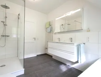 Modernes Badezimmer mit großer, ebenerdiger Dusche und Glasabtrennung.