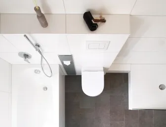 Blick von oben auf ein modernes Badezimmer mit Badewanne, wandhängendem WC und ebenerdiger Dusche. 