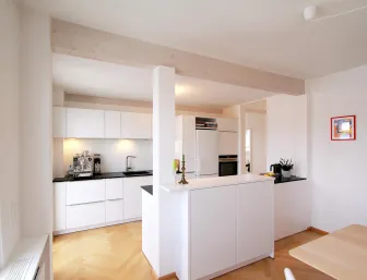 Offene Küche mit weißen Schränken, schwarzen Arbeitsflächen und einer Kücheninsel.