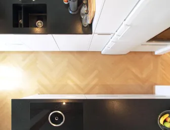 Blick von oben auf eine moderne Küche mit schwarzen Arbeitsflächen und weißen Schränken.