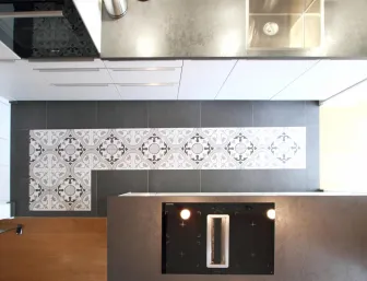 Detailansicht einer modernen Küchenzeile mit stilvollen Fliesen im Vintage-Design. Die Kombination aus grauen Fliesen, einer hochwertigen Arbeitsplatte und einem integrierten Induktionskochfeld verleiht der Küche eine elegante und funktionale Atmosphäre.