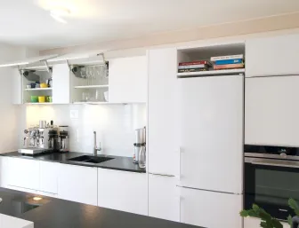 Moderne Küche mit geöffneten Hängeschränken, die Gläser, Tassen und Schüsseln zeigen