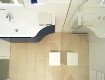 Detailansicht eines modernen Badezimmers mit großzügigem Waschtisch, bodengleicher Dusche und hellen Fliesen für eine zeitlose Eleganz.