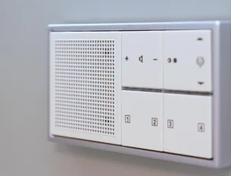 Nahaufnahme eines modernen Steuerelements für die Hausautomation, mit integrierten Tasten zur Steuerung von Licht und Musik.