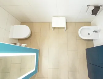 Modern gestaltetes WC mit Bidet und beleuchtetem Spiegel für eine helle und funktionale Badezimmerumgebung.