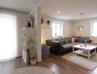 Helles Wohnzimmer mit einer großen Eckcouch, Holzfußboden und modernen Dekorelementen, kombiniert mit einem offenen Raumkonzept und viel natürlichem Licht.