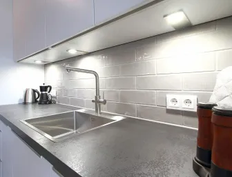 Eine moderne Küchenzeile mit einer dunklen Arbeitsplatte und einer Rückwand aus glänzenden grauen Metrofliesen.