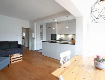 Ein offener Wohn- und Essbereich mit einer modernen, hellgrauen Küche und einer zentralen Kücheninsel.