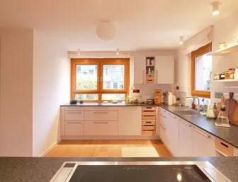 Eine gemütliche Küche mit weißen Schränken und Arbeitsplatten aus dunklem Stein, die sich entlang zweier Wände erstrecken. 