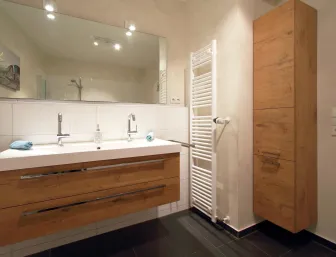 Ein modernes Badezimmer mit einer großen, weißen Doppelwaschbeckenanlage und Holzverkleidung. 