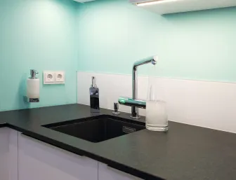 Eine moderne Küchenecke mit einer schwarzen Arbeitsplatte aus Stein und einem eingebauten schwarzen Spülbecken. 