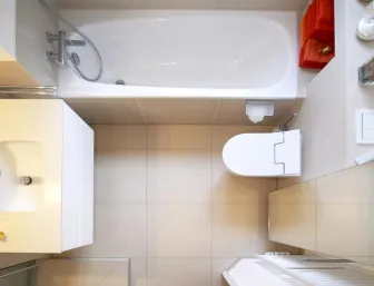 Draufsicht auf ein kompaktes, modernes Badezimmer mit einer weißen Badewanne, einem Waschbecken und einer Toilette.