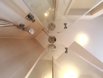 Ansicht einer modernen Dusche mit gläsernen Duschwänden und einer Kombination aus Handbrause und Regenduschkopf aus Edelstahl.