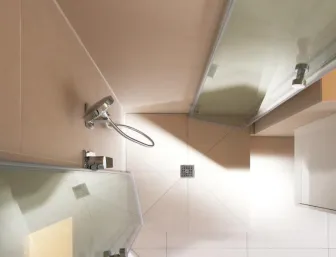 Draufsicht auf eine moderne Dusche mit beigefarbenen Fliesen und einer stilvollen Duscharmatur aus Edelstahl.