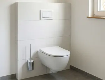 Hängendes WC in einem modernen Badezimmer mit glänzenden Fliesen. Ein Fenster rechts bringt Licht in den Raum.