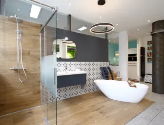 Designbad mit Walk-in-Dusche, freistehender Badewanne und Holzoptik-Fliesen in der Badausstellung von Lassen.