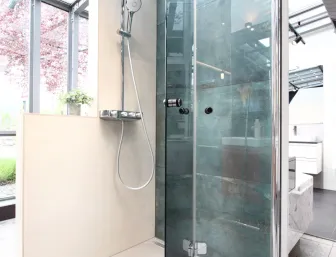 Glasdusche mit Regendusche und modernen Fliesen in der Badausstellung von Lassen.