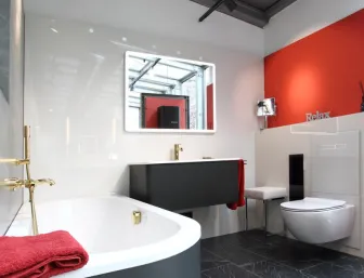 Modernes Luxusbad mit Badewanne, schwarzem Boden und roten Akzenten in der Badausstellung von Lassen.