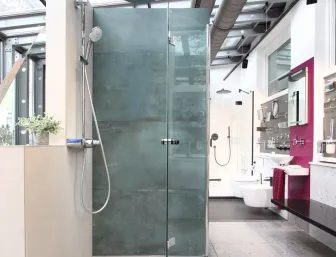 Walk-in-Dusche mit Glaswand, Regendusche und großformatigen Fliesen in der Badausstellung von Lassen.