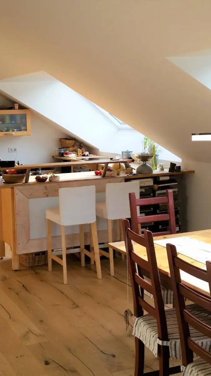 Ein offener Wohnraum in einer Dachgeschosswohnung mit einer modernen Wohnküche und einem angrenzenden Essbereich.