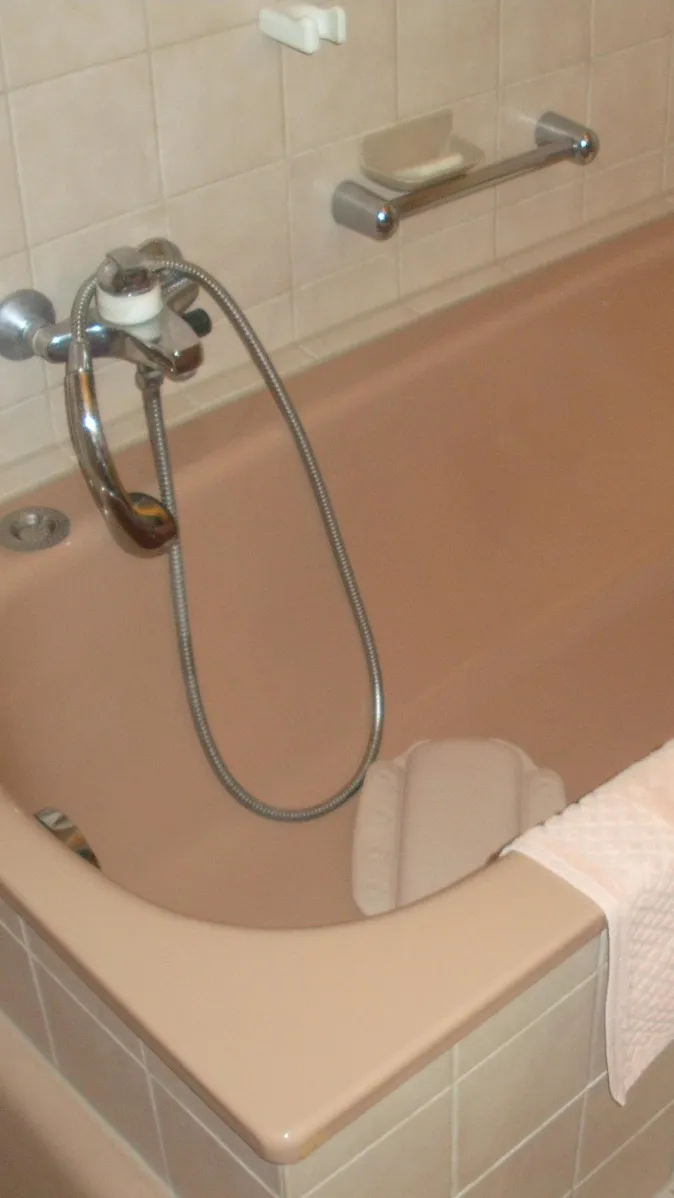 Ein Badezimmer im Retro-Stil mit beigefarbenen Fliesen und sanitären Einrichtungen in passender Farbe.