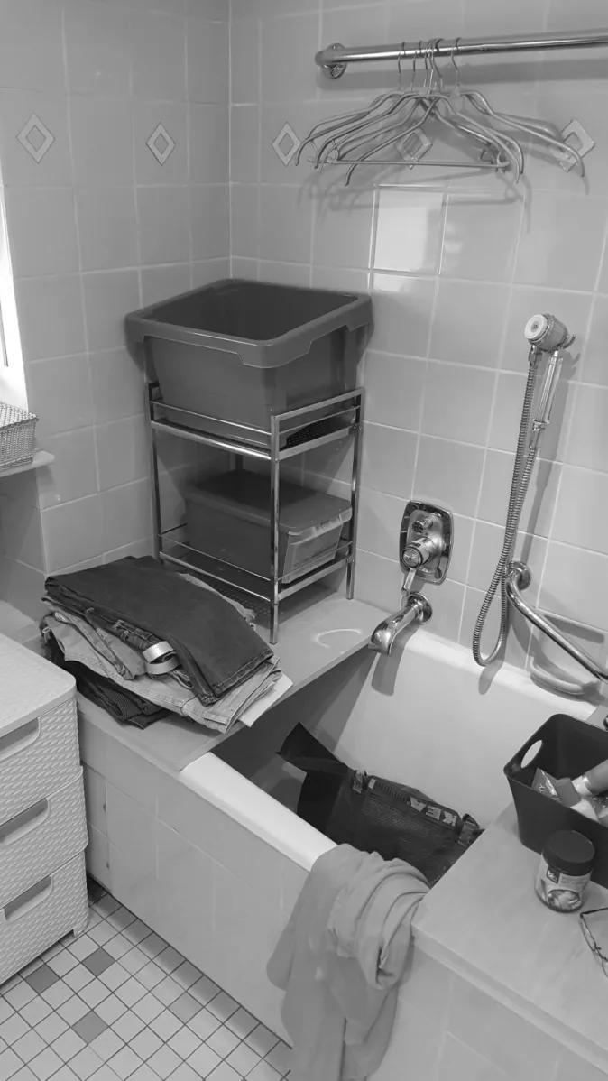 Ein Badezimmer mit einer weißen Badewanne, die als Ablagefläche für Haushaltsgegenstände genutzt wird. 