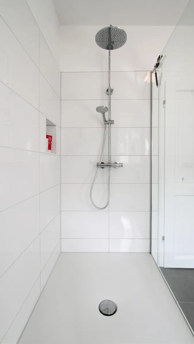 Eine moderne Walk-In-Dusche mit einer Regendusche und einer separaten Handbrause, beide aus Edelstahl. 